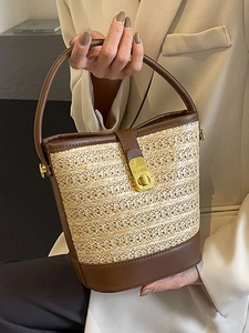 Minimalist straw bucket bag with brown leather trim and golden metal swivel lock closure