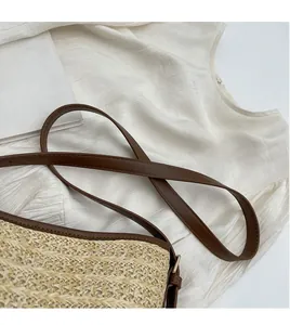 Detail of adjustable brown leather shoulder strap on a woven straw bucket bag