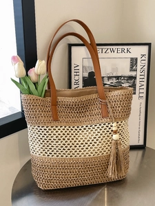 Schicke gestreifte Strohtasche mit braunen Lederriemen und Quasten für den Sommerurlaub