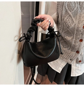 Detail view of stylish black scrunchie cloud bag with bow accents and soft leather texture