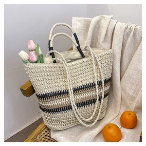 Close-up of woven straw tote bag with black and brown stripes and round handles
