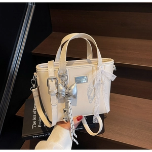 Detail of cream white leather bucket bag with silver bow charm and lace decoration