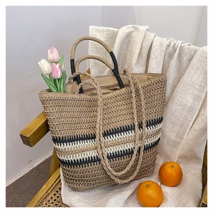 Detail of woven straw tote bag with black stripes and tulips in a lifestyle setting