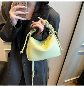 Detail of lime green ruched handle and knot drawstring on soft leather shoulder bag