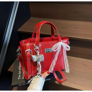 Detail of red wax leather bucket bag with white lace bow and silver heart pendant charm
