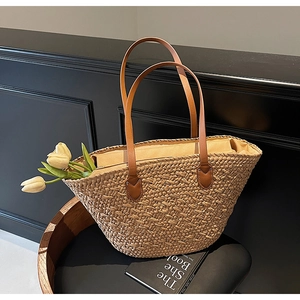 Detail of hand-woven straw tote bag with brown leather straps and decorative white tulips