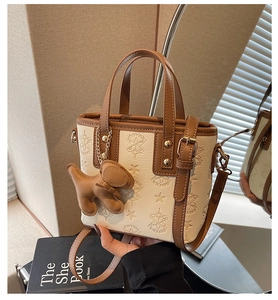 Détail de l'embossage étoilé et du logo sur le sac seau beige avec bordure en cuir