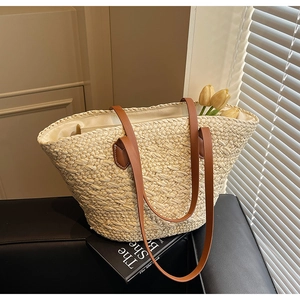 Detail of hand-woven straw tote with premium brown leather handles and interior lining