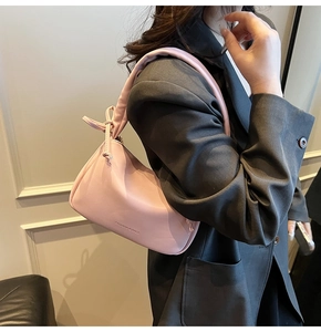 Close-up of pink pleated pillow bag with knotted strap and fashion text detail