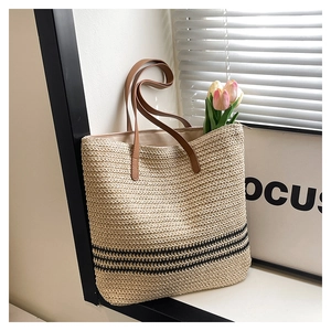 Close-up of woven tote bag with black stripes and elegant brown leather handles