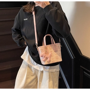 Détail d'un sac seau rose clair gaufré avec un charmant pendentif chien en peluche doux