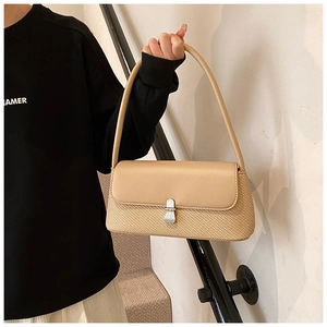 Détail du sac porté épaule tissé beige avec rabat en cuir et fermoir métallique