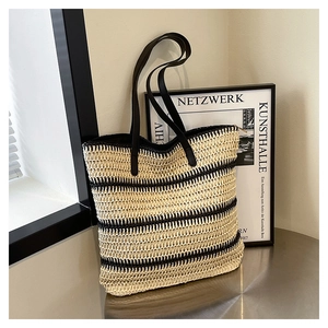 Detailed view of striped woven straw tote bag with black leather handles and texture