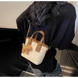 Détail du sac beige avec motif d'étoiles, pendentif chien et crochet métallique