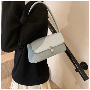 Détail d'un sac sous le bras bleu clair avec texture tissée et fermoir en métal argenté