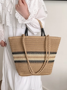 Large hand-woven straw tote bag with black stripes and shoulder straps for beach travel