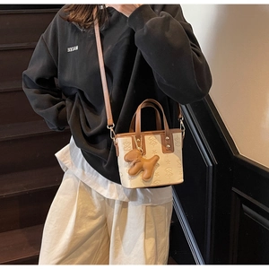 Détail du sac seau crème avec gaufrage étoilé et breloque chien en cuir marron