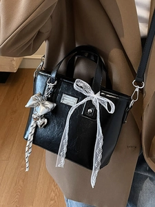 Minimalist black oil wax leather bucket bag with lace bow and silver butterfly charm