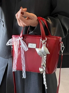 Red glossy patent leather bucket bag with lace bow and silver heart pendant detail