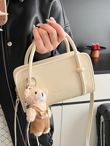 Minimalist cream-colored square crossbody bag with thin handles and cute bear charm