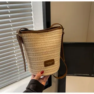 Detailed view of woven straw bucket bag with leather strap and premium metal buckle