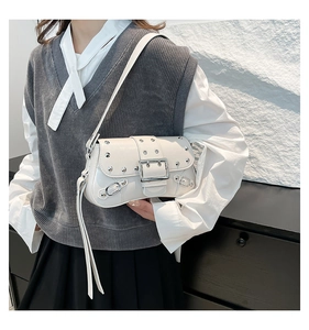 Close-up detail of silver studs and buckle on an off-white leather shoulder bag