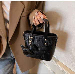 Détail du sac seau noir gaufré avec motifs d'étoiles et breloque chien au manche