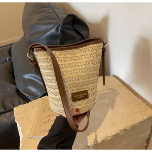 Detail of hand-woven straw texture and premium brown leather trim on bucket bag