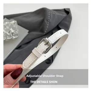 Detail of white crocodile pattern adjustable shoulder strap with silver buckle hardware