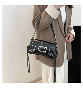 Detail of black punk-style shoulder bag with silver rivets and metal buckle hardware