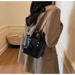 Détail du sac seau noir avec texture étoile gaufrée et breloque chien mignonne