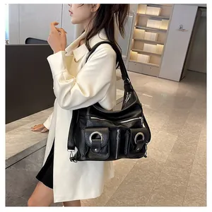 Detail of black pebbled leather tote bag with metallic ring pockets and wide strap