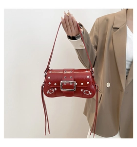 Detail of red punk shoulder bag featuring silver rivets and a large square buckle