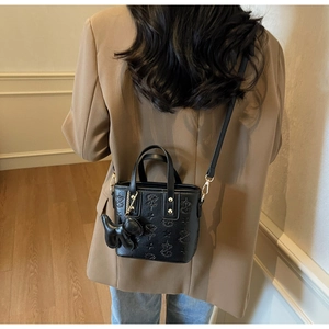 Détail d'un sac seau noir gaufré avec motifs d'étoiles et charmant pendentif de chien