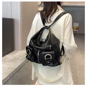 Detail view of a black multi-pocket fashion backpack with silver metal buckles on a model