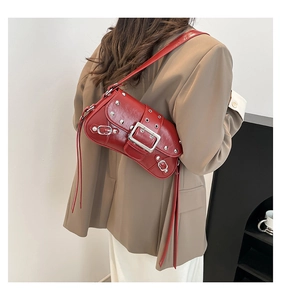 Détail d'un sac bandoulière rouge style punk avec des rivets argentés et boucles en métal