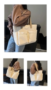 Detail of multi-pocket nylon tote bag showing front zip compartments and wide shoulder strap