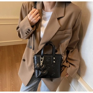 Détail du sac seau en cuir gaufré noir avec motifs d'étoiles et breloque poupée