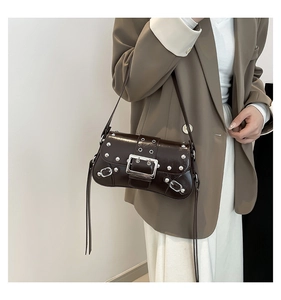 Detail of dark brown leather underarm bag featuring silver rivets and long fringes