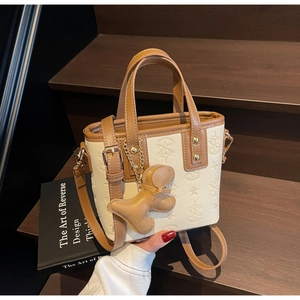 Détail du sac seau en PU crème gaufré avec bordure marron et breloque chien mignonne