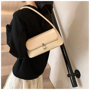 Détail du sac sous le bras blanc crème avec texture tissée et fermoir en métal argenté