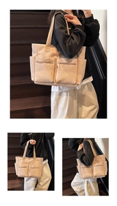 Detail view of large beige nylon tote bag showing multiple functional zipper pockets