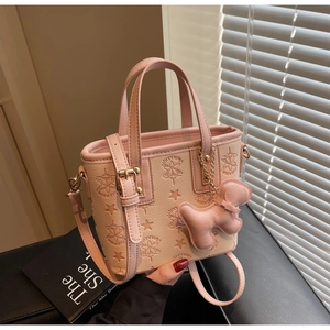 Détail du sac seau rose avec motif d'étoiles, breloque chien et bandoulière