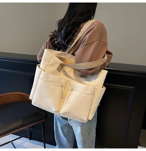 Detail view of the multi-pocket nylon tote bag shown on a model for scale and utility