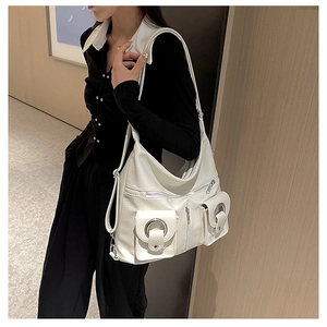 Detailed view of white hobo tote bag featuring multiple pockets and silver metal rings