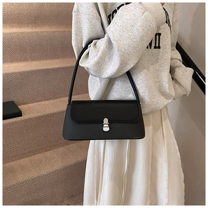 Vue détaillée d'un sac à bandoulière noir avec texture et fermoir cylindrique en métal argent