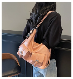 Detail of pink oil wax leather tote showing front flap pockets and a brown bear charm