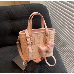 Détail du sac seau beige gaufré avec bordure rose et pendentif petit chien