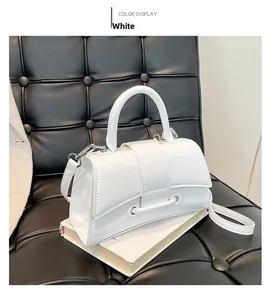 Detailed view of white hourglass handbag with textured finish on black leather surface