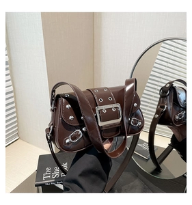 Détail d'un sac à bandoulière en cuir verni marron foncé avec rivets et œillets argentés